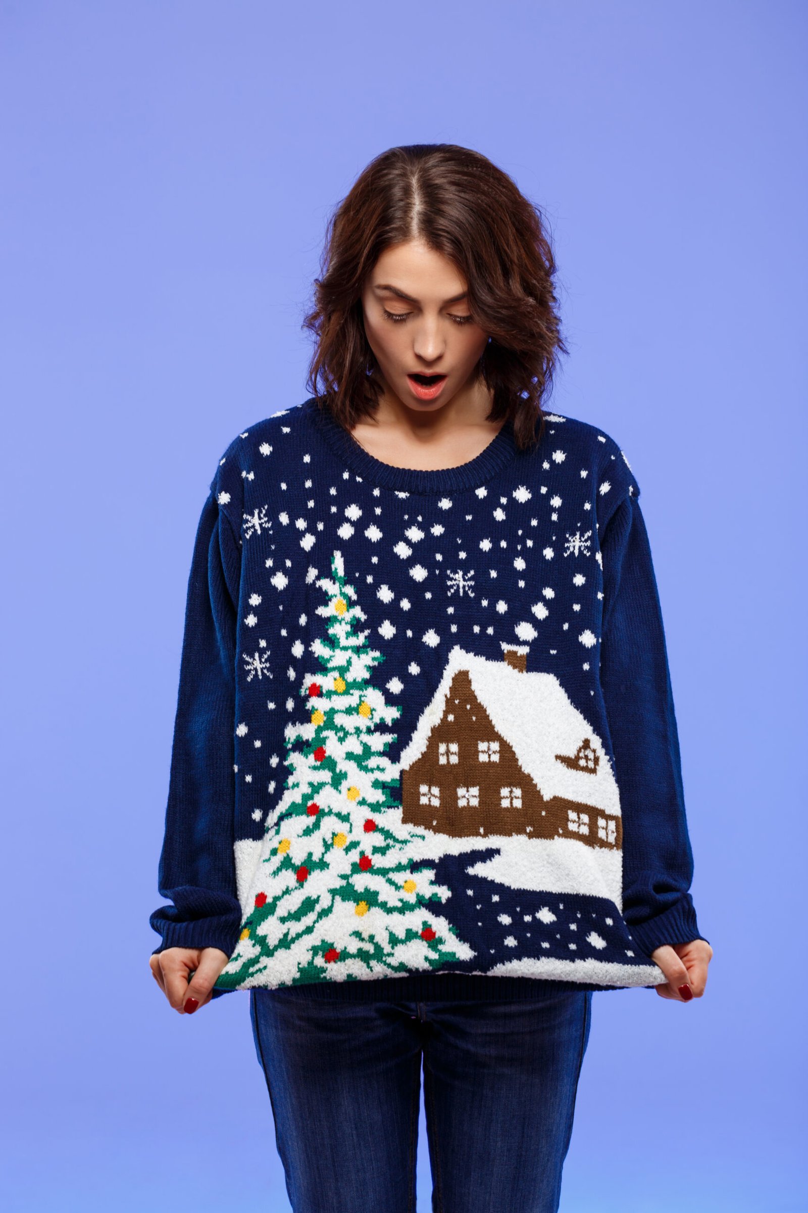 belle-jeune-fille-brune-amusee-en-pull-tricote-confortable-posant-sur-le-mur-bleu-